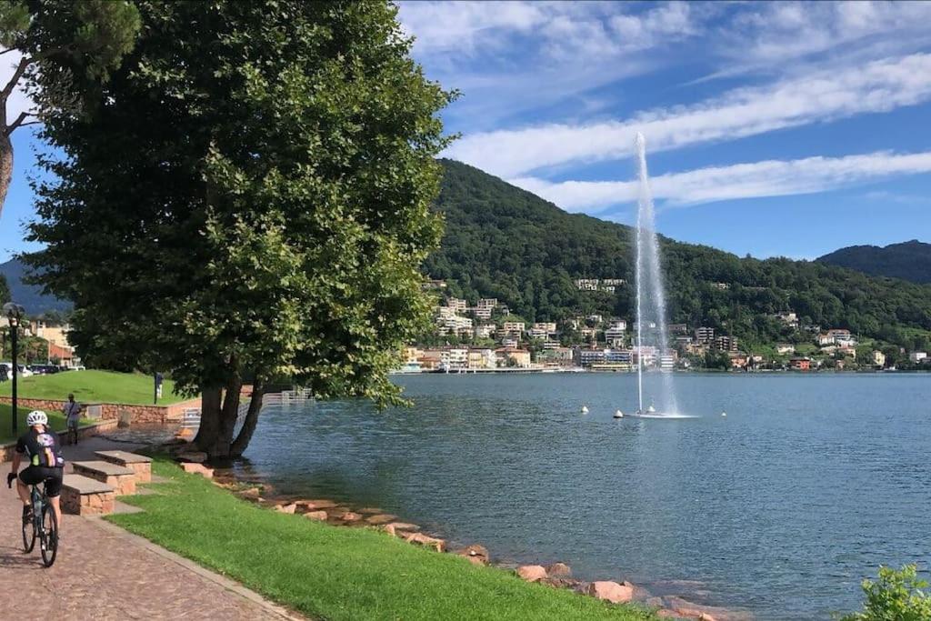 拉韦纳蓬泰特雷萨Tresa Bay House - Lugano Lake的骑着自行车的人在湖边,有喷泉