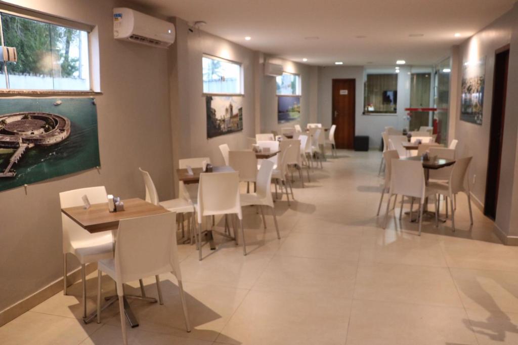 劳鲁-迪弗雷塔斯奥尼克斯机场酒店的一间在房间内配有白色椅子和桌子的餐厅