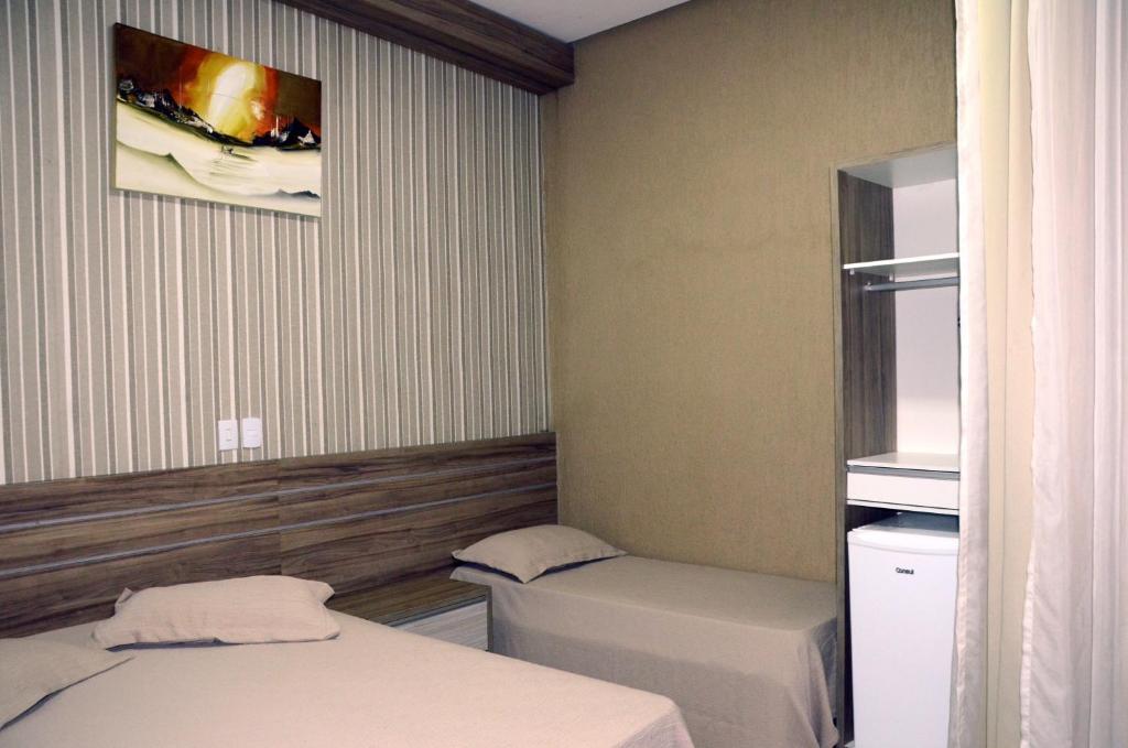 邦热苏斯-达拉帕Hotel Grutta的小房间设有两张床,墙上挂着一张照片