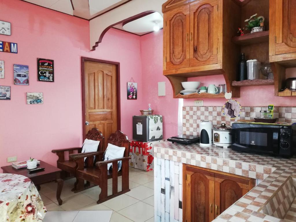 公主港Agimats Crib Palawan的厨房设有粉红色的墙壁和木制橱柜。