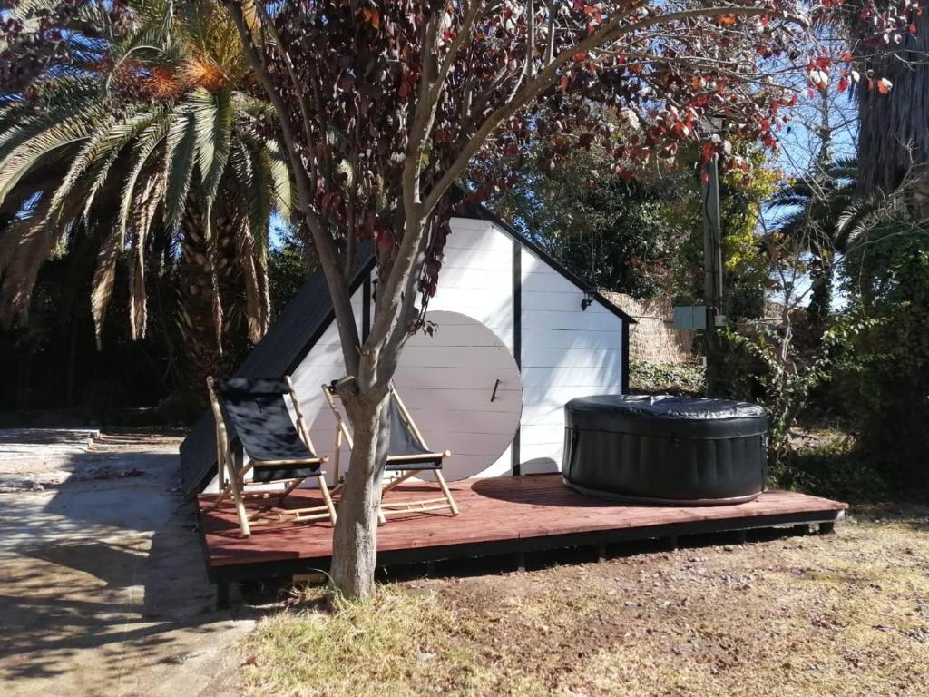 梅利皮亚Lodge Spa Melipilla的树旁的帐篷,配有两把椅子和一桶桶