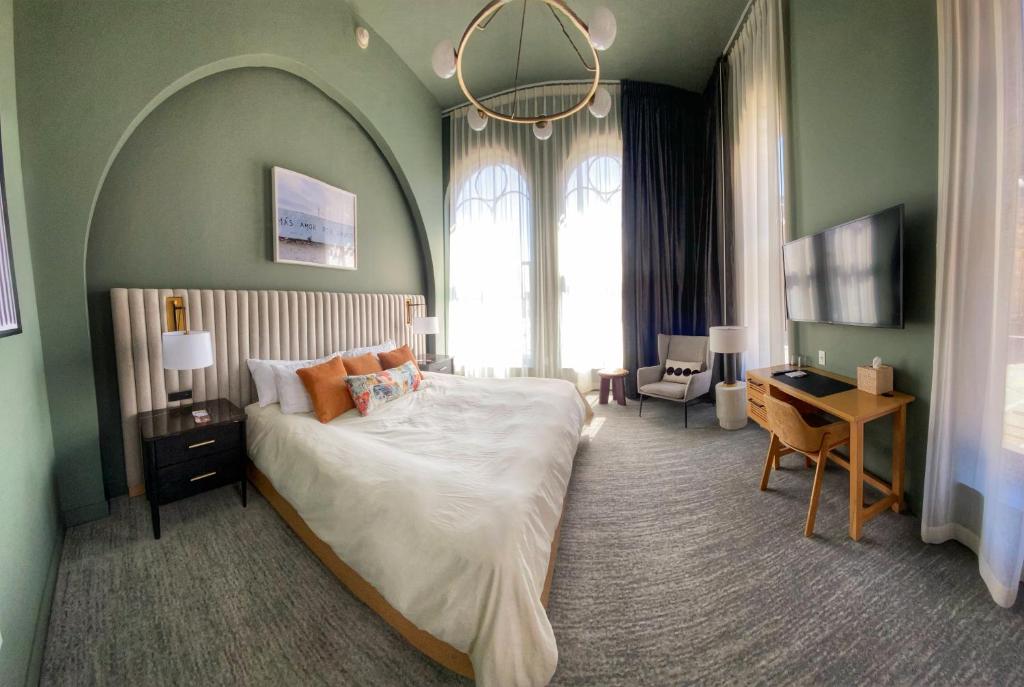 密尔沃基Kinn Guesthouse Downtown的一间卧室配有一张大床、一张书桌和窗户。
