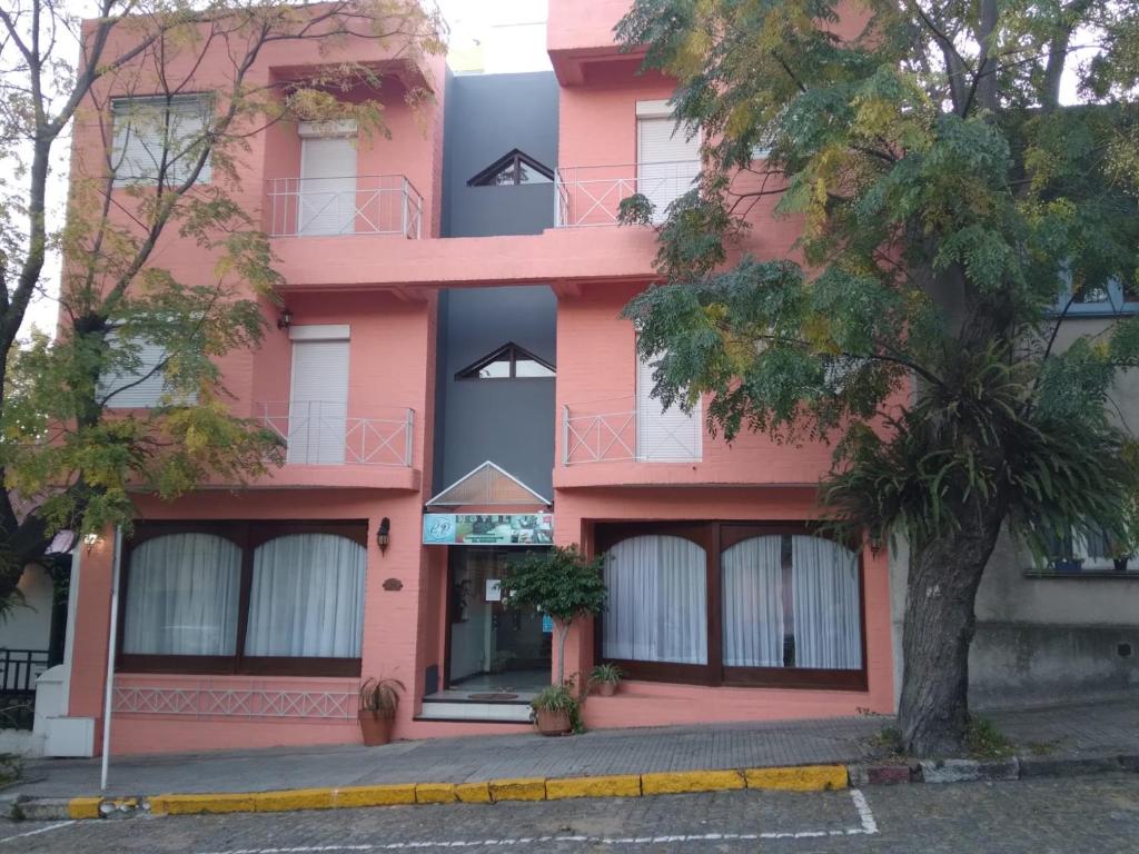 科洛尼亚-德尔萨克拉门托Hotel Perla del Plata的前面有棵树的粉红色建筑
