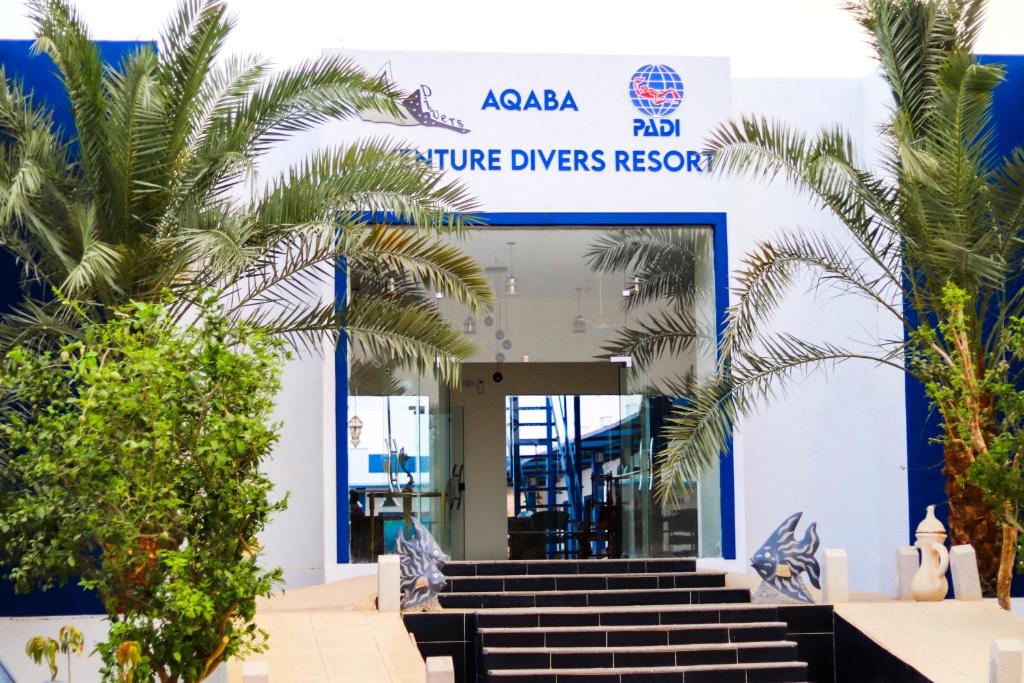 亚喀巴Aqaba Adventure Divers Resort & Dive Center的蓝白色的建筑,有楼梯,棕榈树