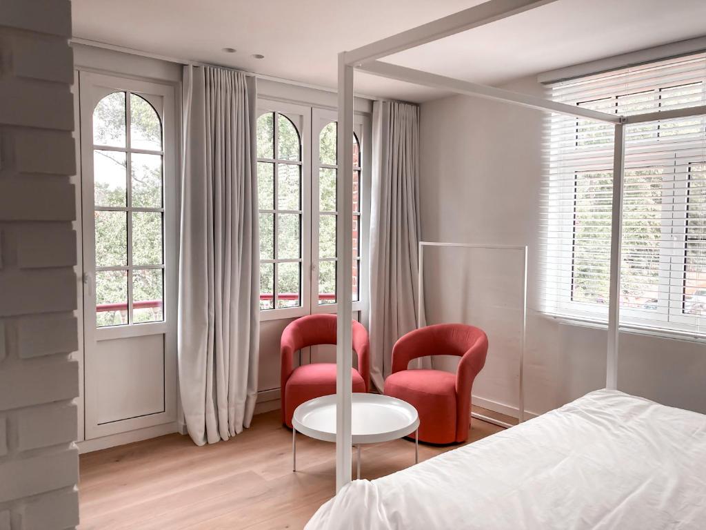 德哈恩Doux Foyer的一间卧室设有两张红色椅子和一张床及窗户
