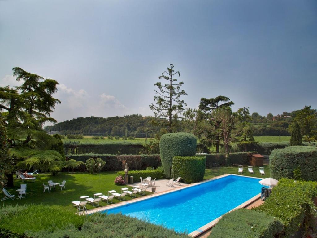 巴多利诺Veronello Resort的花园内的游泳池,花园内有椅子和树木