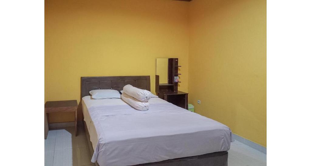 TilamutaJulista House Mitra RedDoorz的一间卧室配有带白色床单和枕头的床。
