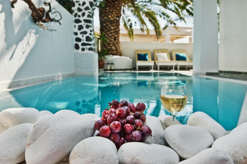 费拉加拉太别墅酒店的一杯葡萄酒和一碗葡萄,在游泳池旁边