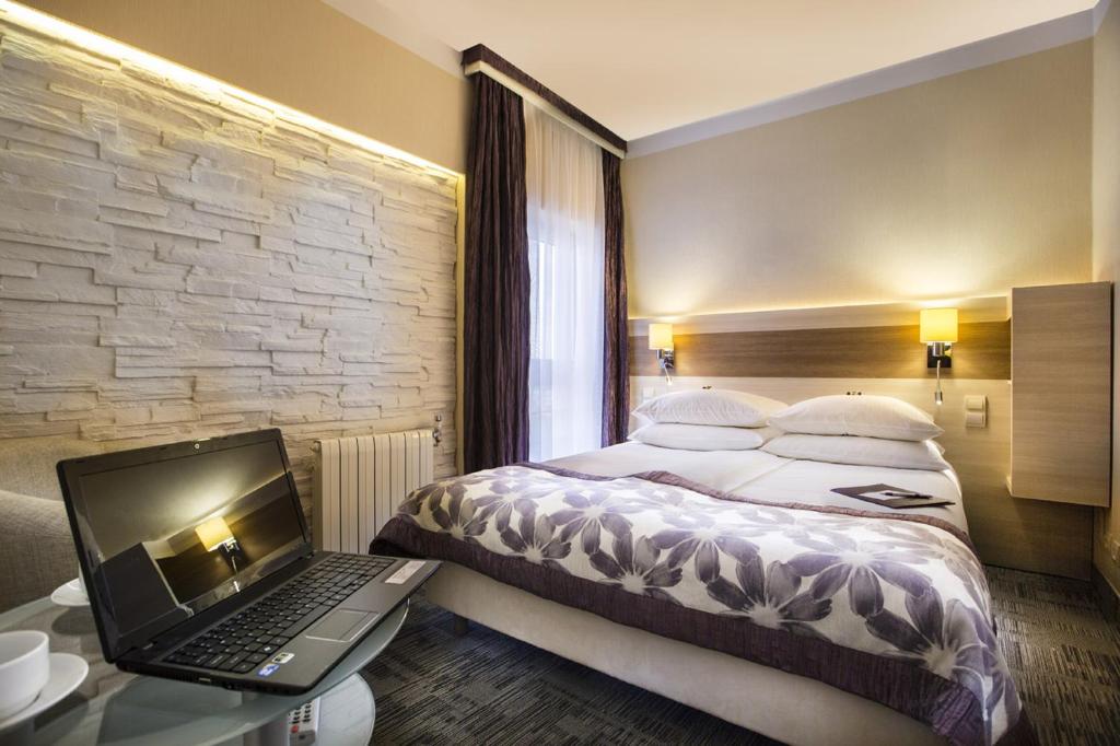 比亚韦斯托克三重奏舒适酒店的一间卧室配有一张床和一张桌子上的笔记本电脑