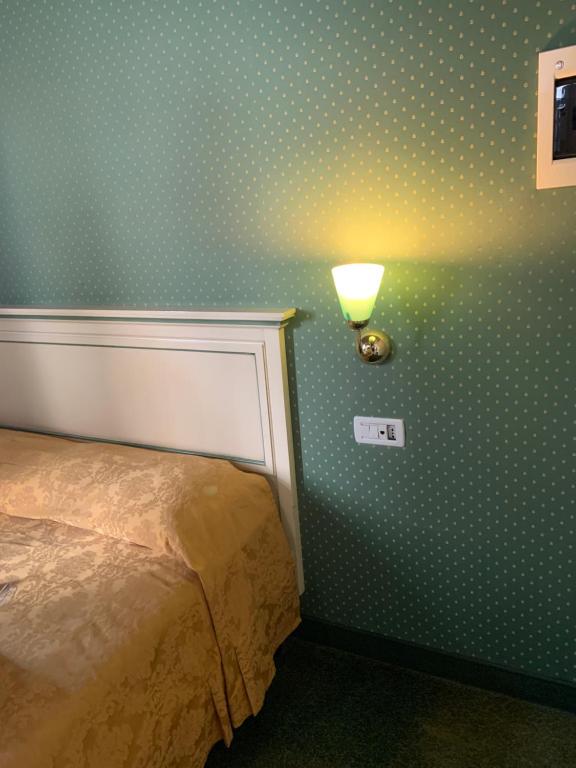威尼斯Locanda Ruga Rialto的一间卧室配有波卡圆点壁纸和墙上的灯。
