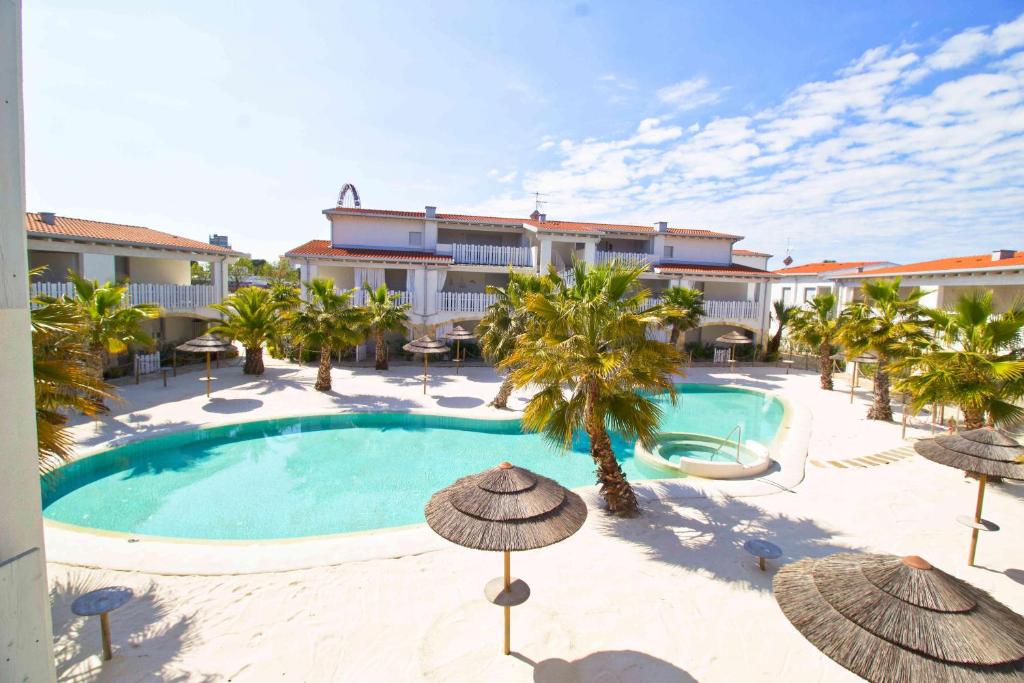 利多迪耶索罗Cala Blu的酒店前方的游泳池设有遮阳伞和棕榈树。