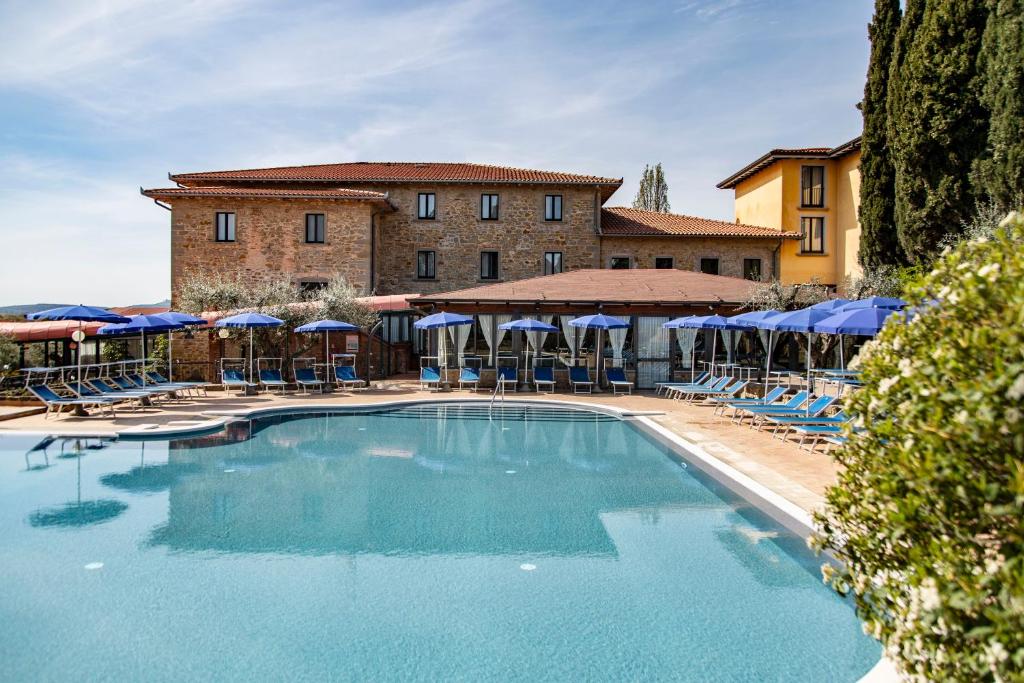 特拉西梅诺湖畔帕西尼亚诺Hotel Villa Paradiso的大楼前的带椅子和遮阳伞的游泳池