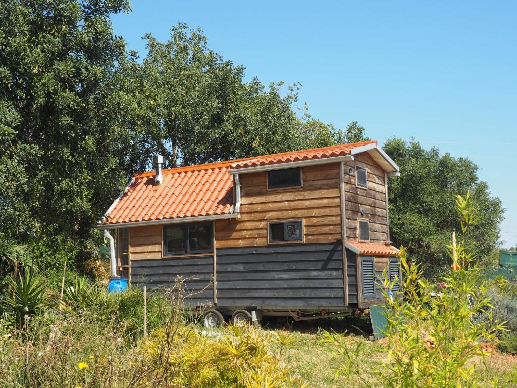 EstevaisTiny house eco resort的田野上带橙色屋顶的木屋
