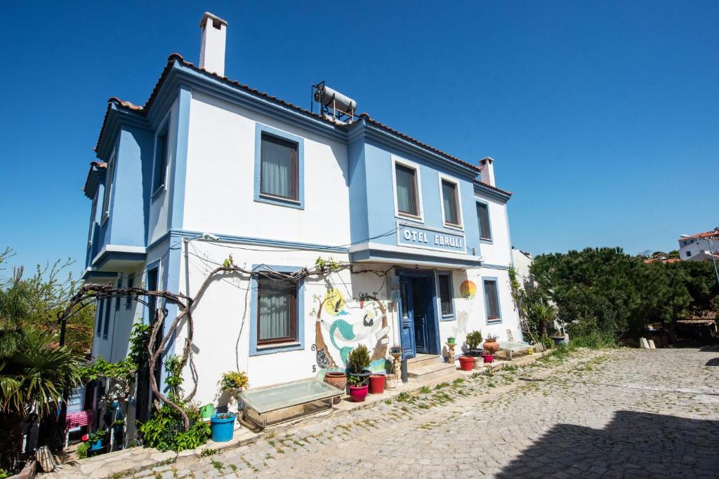 博兹贾阿达岛Ebruli Hotel的鹅卵石街道上白色的白色房子,蓝色的饰物