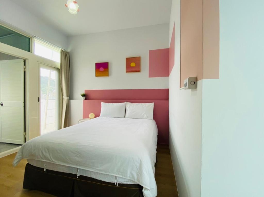 台东小逗民宿的卧室配有白色床和粉红色床头板