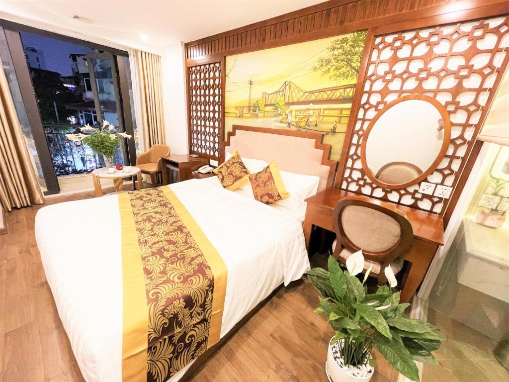 河内DE LA SOIE Hotel & Travel的酒店客房设有一张床,墙上挂有绘画作品