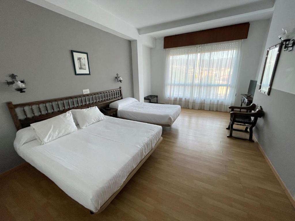 蓬特德乌梅Hotel Eumesa的卧室配有一张白色大床和一张书桌