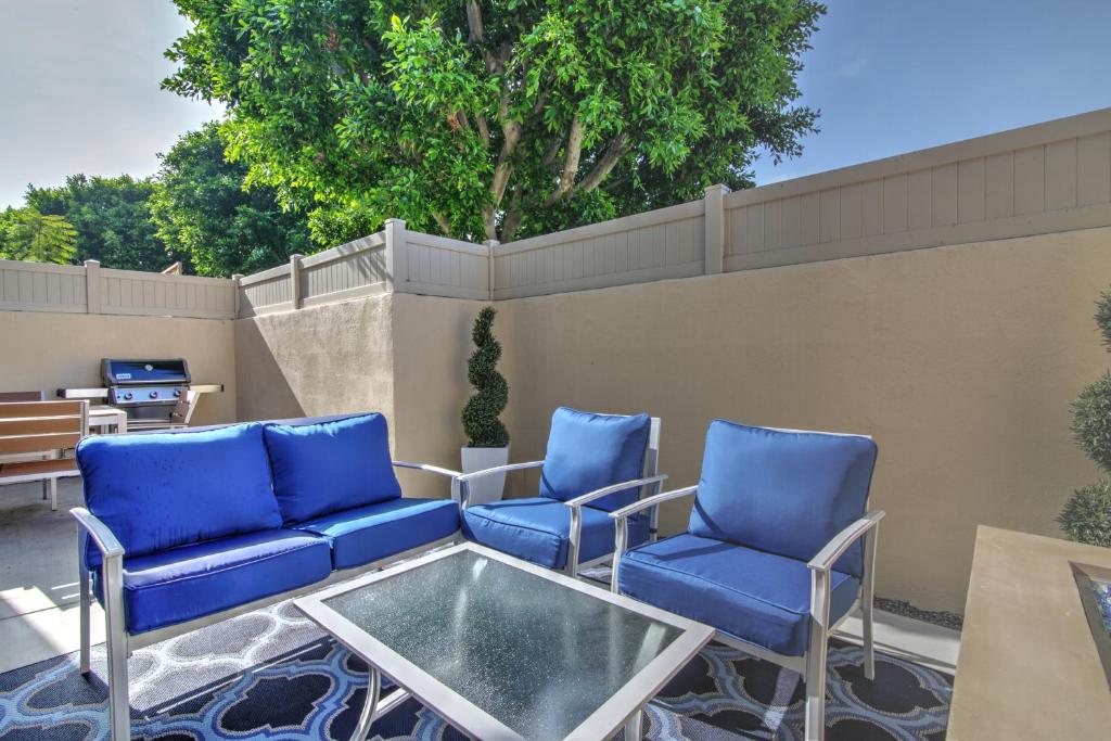 安纳海姆Doorstep to Disneyland Condos的庭院设有蓝色的椅子和玻璃桌