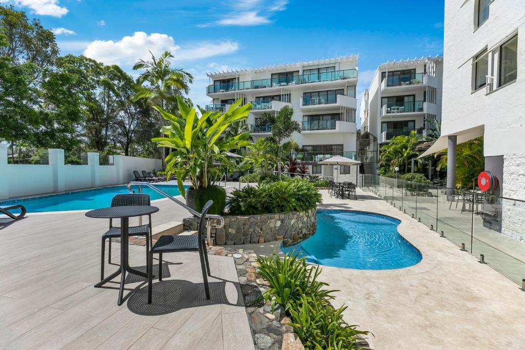努萨角太阳湖度假酒店的公寓庭院设有桌椅和游泳池。