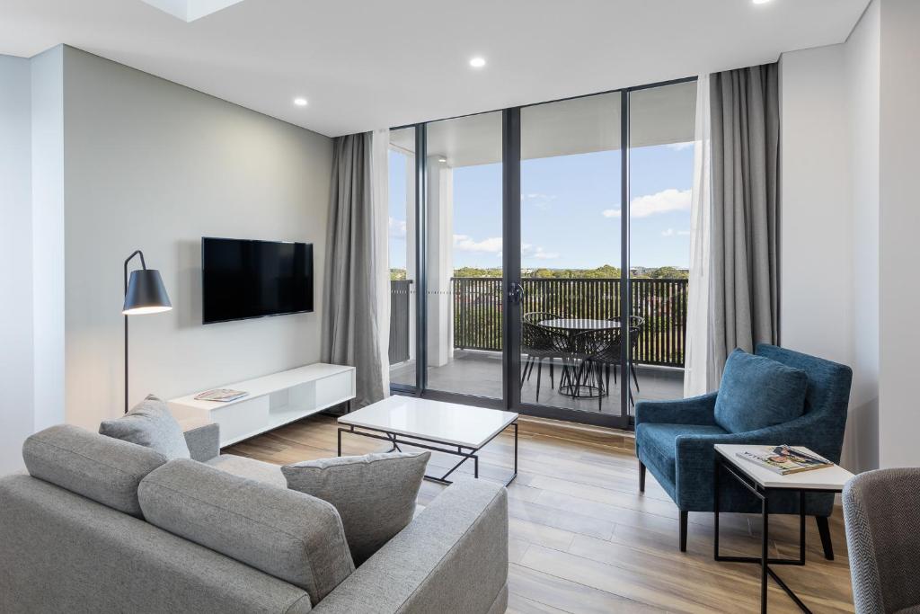 悉尼Meriton Suites Coward Street, Mascot的客厅配有沙发、椅子和电视