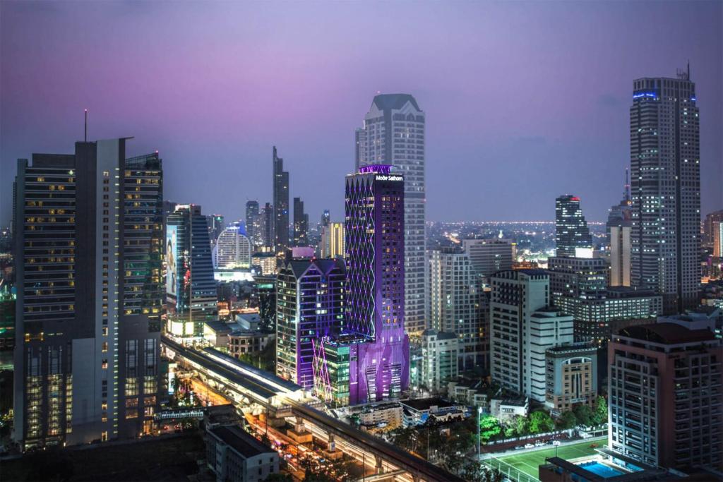 曼谷Mode Sathorn Hotel - SHA Extra Plus的一座城市,在晚上点燃很多高楼