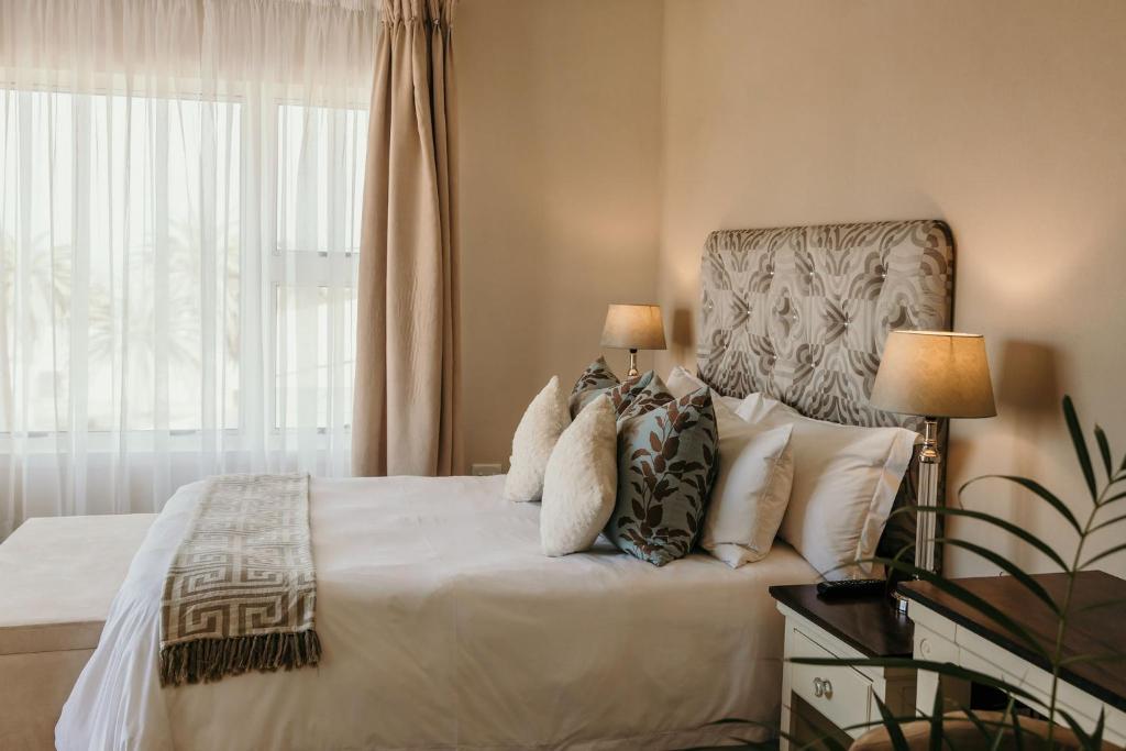斯瓦科普蒙德Artemis Hotel Swakopmund的卧室配有带枕头的床铺和窗户。