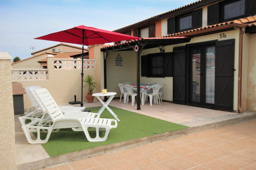 波尔蒂拉盖Belle villa de vacances climatisée, residence TAMARIS, wifi, 2 chambres 4 à 6 couchages, accès payant pour les piscines et animations , PORTIRAGNES PLAGE LRTAMA57的庭院配有白色的椅子、桌子和遮阳伞