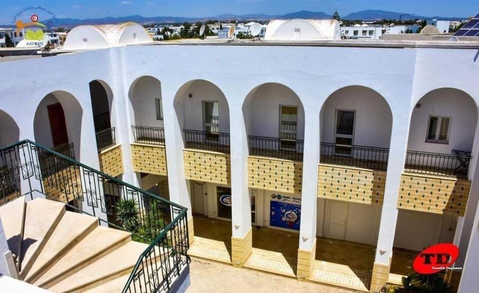 Hammamet SudRésidence aladin的一座带拱门和楼梯的大型白色建筑