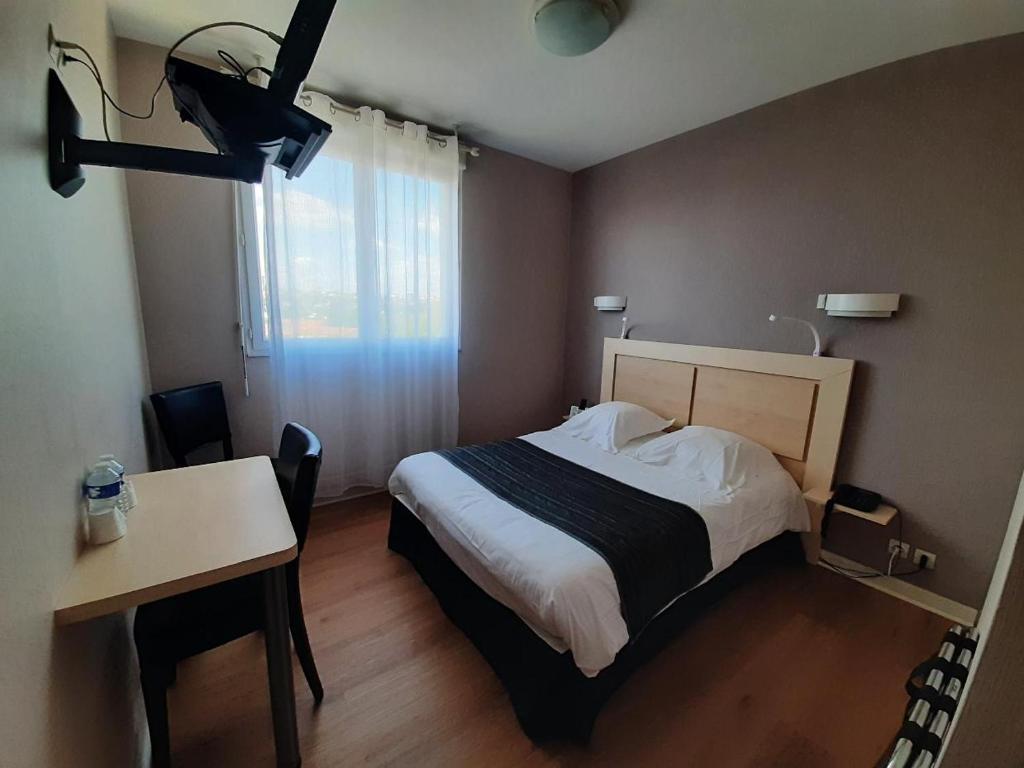 Saint-Jean-de-Thouars圣让酒店的一间卧室配有一张床、一张桌子和一张书桌