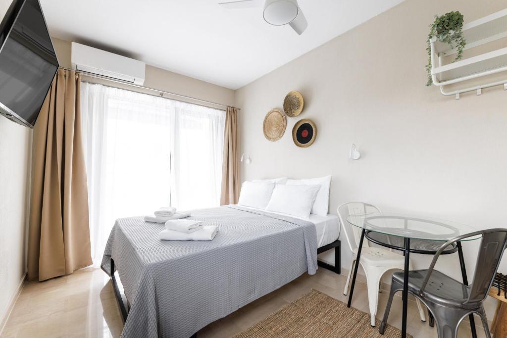 塞萨洛尼基Boho Rooms的一间卧室配有一张床、一张桌子和一台电视。