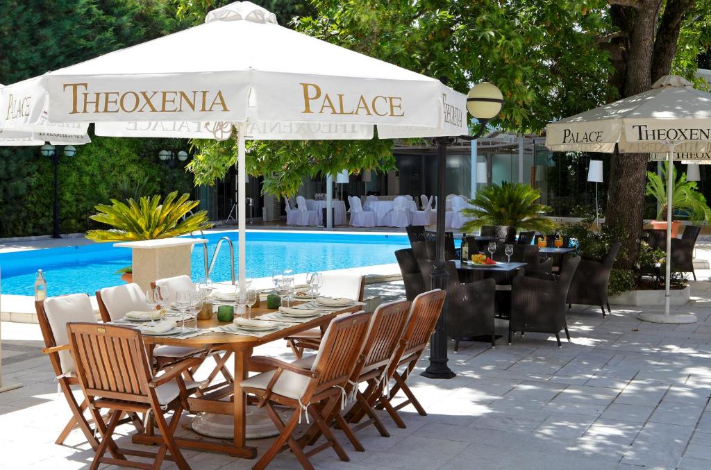 雅典塞奥克塞尼亚酒店的游泳池旁配有桌椅和遮阳伞