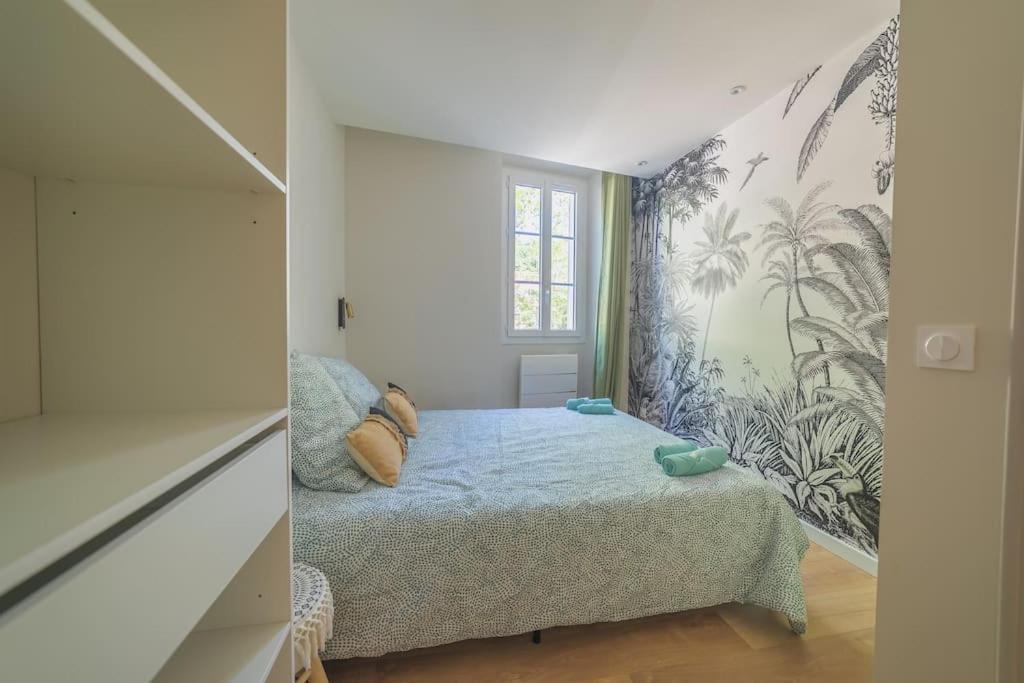 科洛布里埃Le Palm Appartement élégant & Design En Bord Rivière的一间小卧室,配有床和壁画