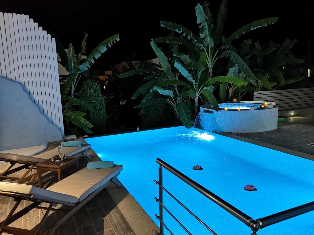 拉多斯Valantas Garden Suite的游泳池在晚上配有两把椅子和一张桌子