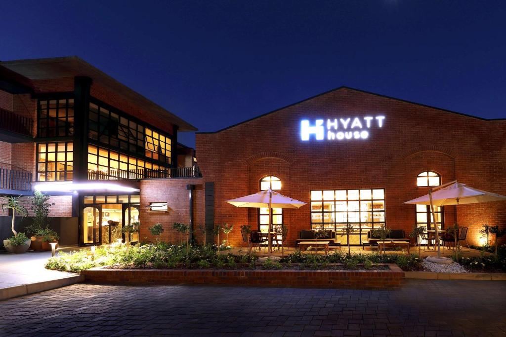 约翰内斯堡Hyatt House Johannesburg, Sandton的一座带照明标志的大型砖砌建筑