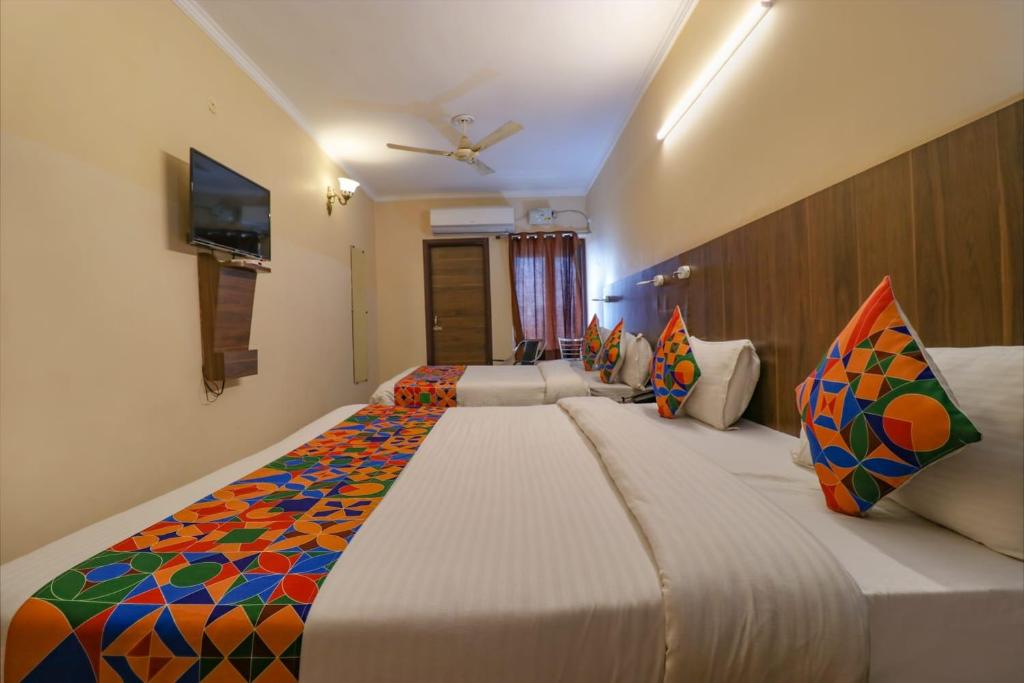 阿姆利则Hotel Golden Sunrise inn的一间卧室配有一张带色彩缤纷枕头的大床