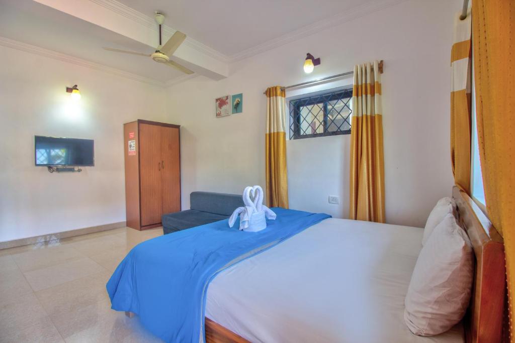 巴加Baga Beach Rosy Inn的一间卧室配有一张带蓝色毯子的大床