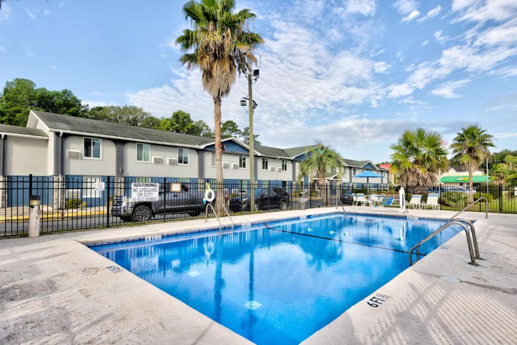 萨凡纳Days Inn by Wyndham Savannah Gateway I-95的一个带围栏和棕榈树的游泳池