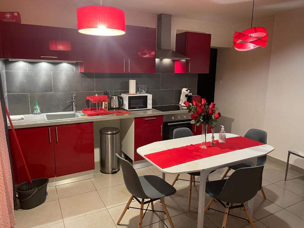 圣艾蒂安Red lights grand appartement的厨房配有红色橱柜和白色桌椅
