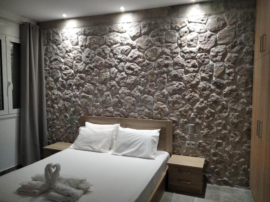 埃尔米奥尼Estia - Brand new apartment in Ermioni Village的一间卧室设有石墙和床