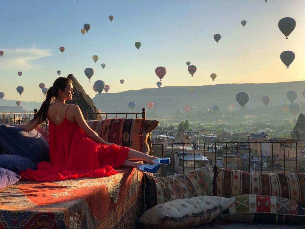 格雷梅维斯塔窑洞酒店的坐在床上的女士,带热气球