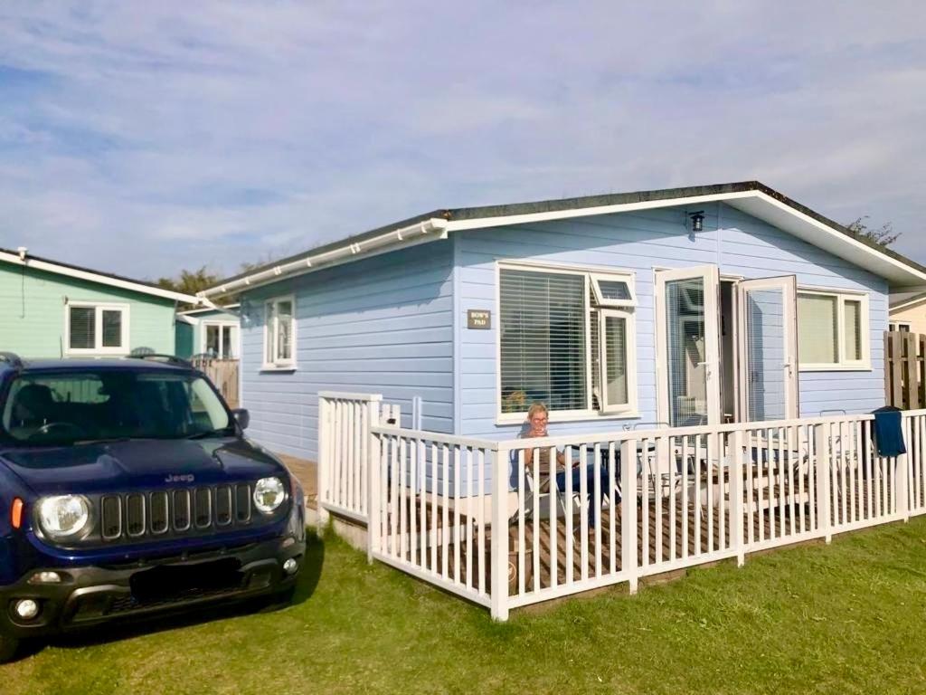 GwithianHoliday Chalet at Gwithian Sands in Cornwall的停在蓝色房子前面的吉普车