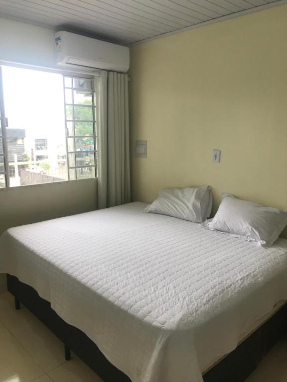 沙佩科Loft confortável no Centro的卧室配有白色的床和窗户