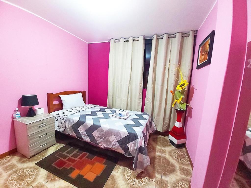 利马Samay Wasi - Aeropuerto的粉红色的卧室,配有床和梳妆台