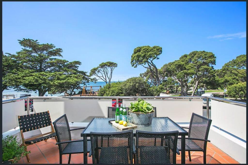 伯恩特隆斯代尔Lonnie Beach View Apartment的阳台配有桌椅和桌子及饮料