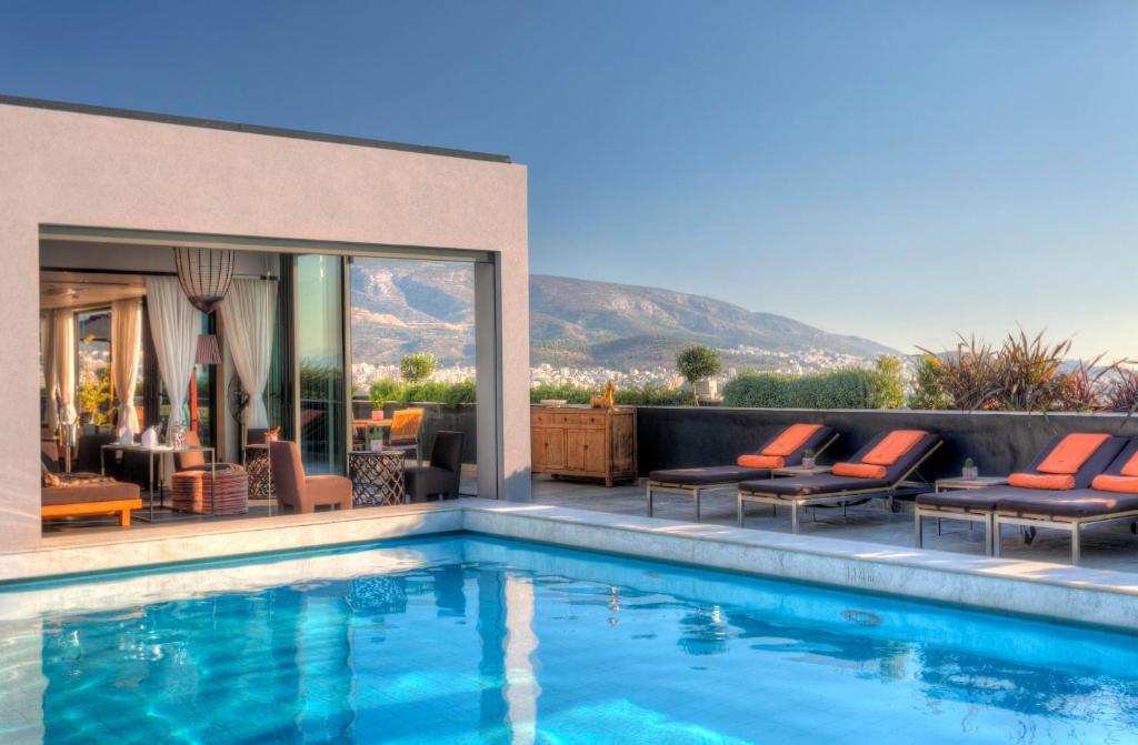 雅典President Hotel Athens的一个带躺椅的游泳池以及一座房子