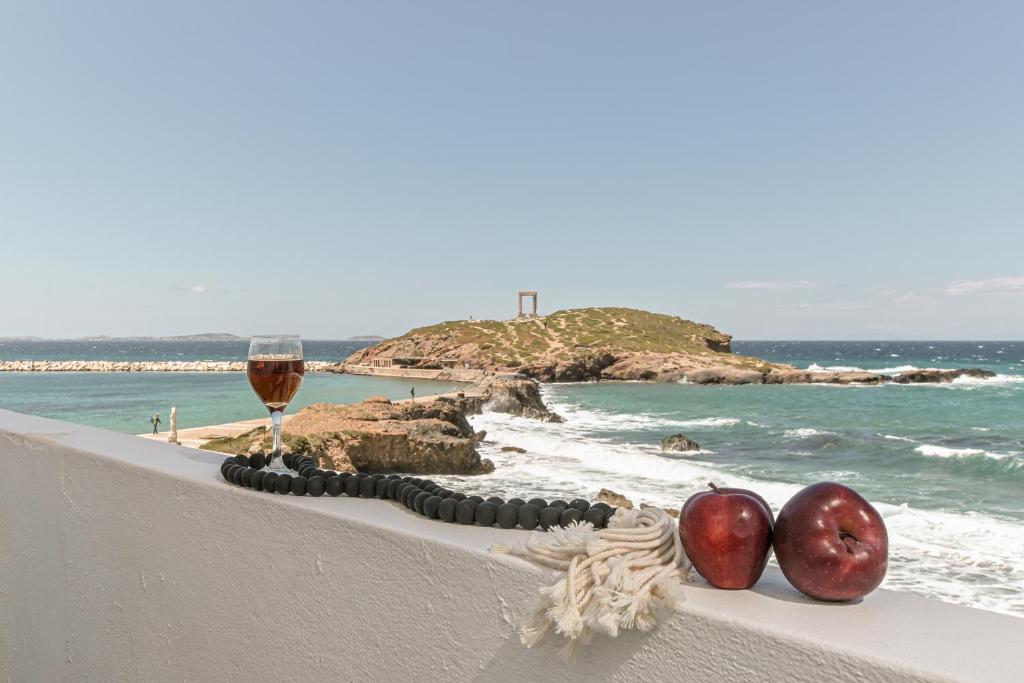 纳克索乔拉Flèria Seaview Suites的一杯葡萄酒和两颗苹果在靠近大海的树 ⁇ 上