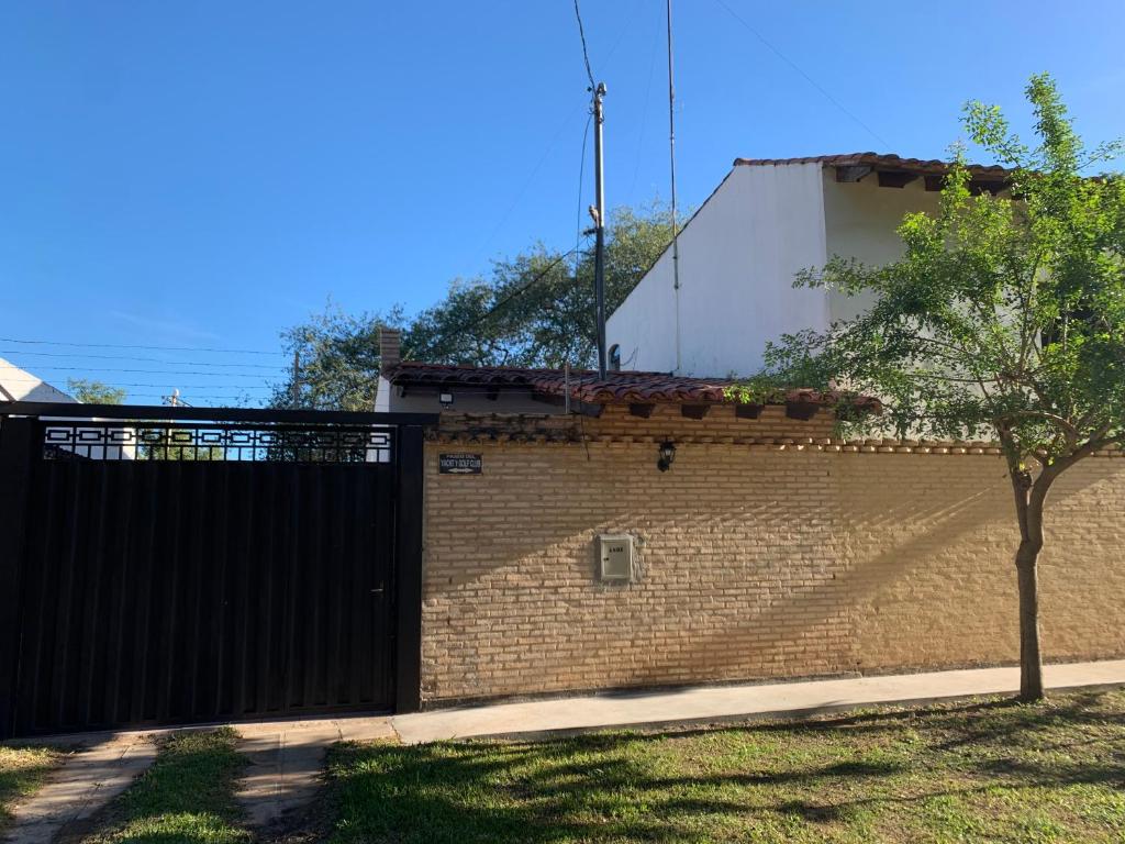 亚松森CostaMansa House, a orillas del Rio Paraguay的砖墙,有黑色的大门和一棵树