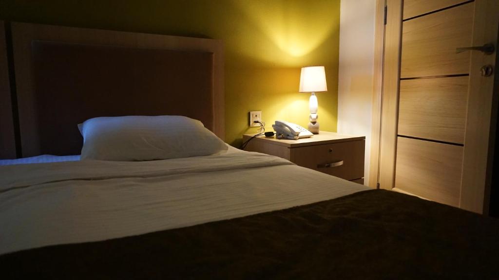 巴库Flamingo Hotel Baku的一间卧室,配有一张床和床头柜上的电话