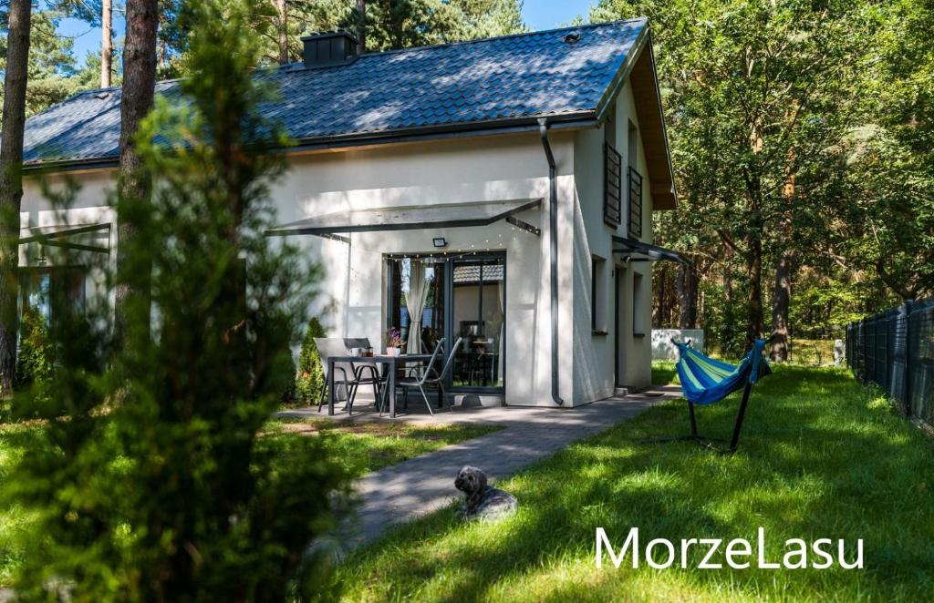 奥斯特罗沃Domek MorzeLasu Ostrowo Jastrzębia Góra的庭院内带蓝色吊床的白色小房子