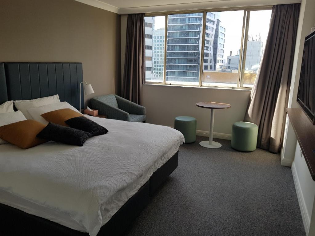 悉尼Chatswood Hotel的卧室配有床、椅子和窗户。